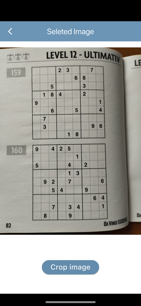 SoLuLu - A photo of a printed Sudoku puzzle book being cropped within the SoLuLu app interface.