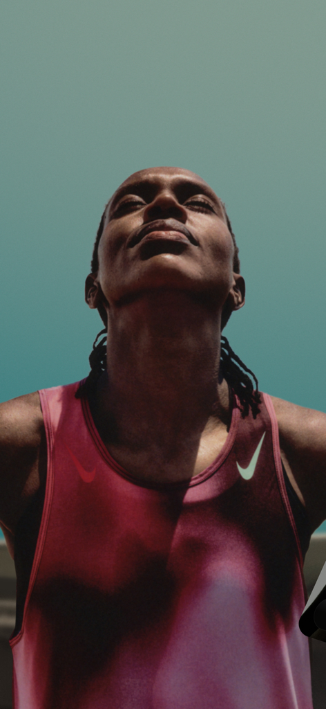 Athletin in einem pinkfarbenen Nike-Tanktop blickt mit geschlossenen Augen nach oben