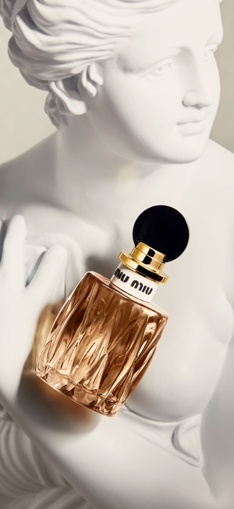 Bloomingdale's: Online Store - Flacon de parfum Miu Miu devant une statue en marbre blanc