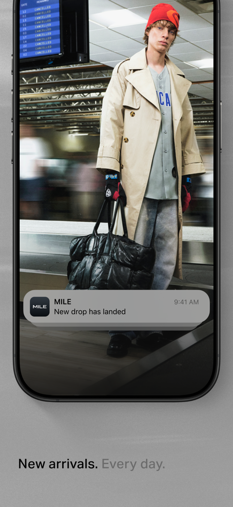 Smartphone screen displaying a MILE app notification for a new fashion drop over a model in high-end streetwear.