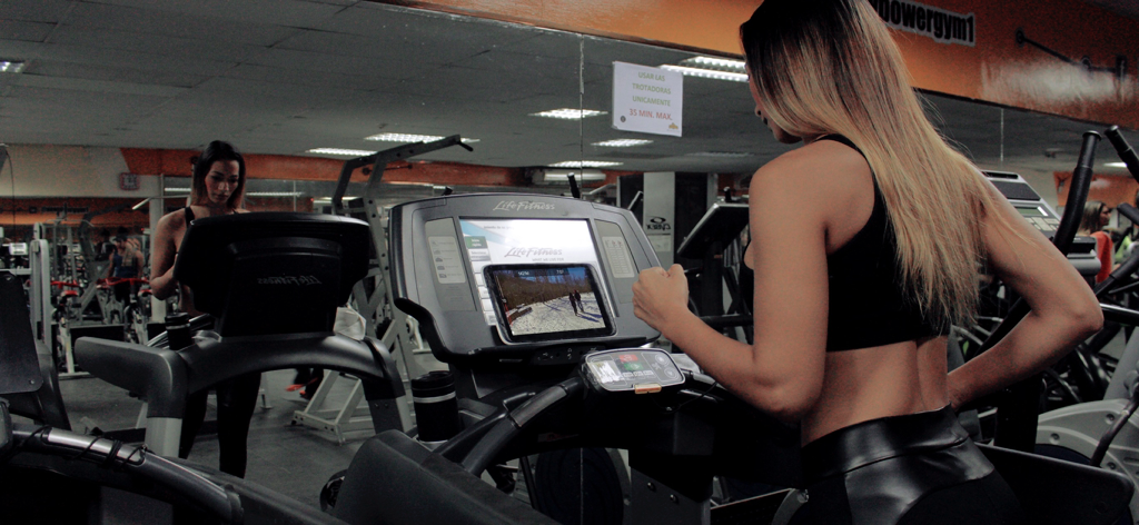 Woman using a treadmill while watching a scenic virtual route on a tablet