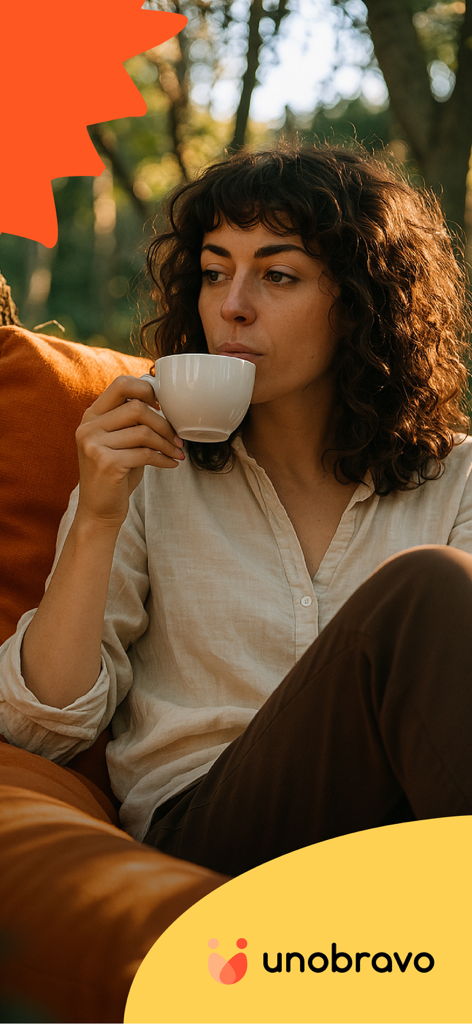 Una mujer joven con el pelo rizado tomando una taza de café en un entorno tranquilo al aire libre con el logo de Unobravo