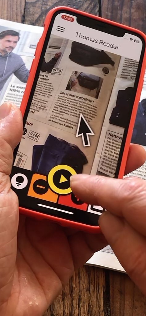 Thomas Reader - A person using the Thomas Reader app on a smartphone to scan and read a magazine page with high contrast buttons