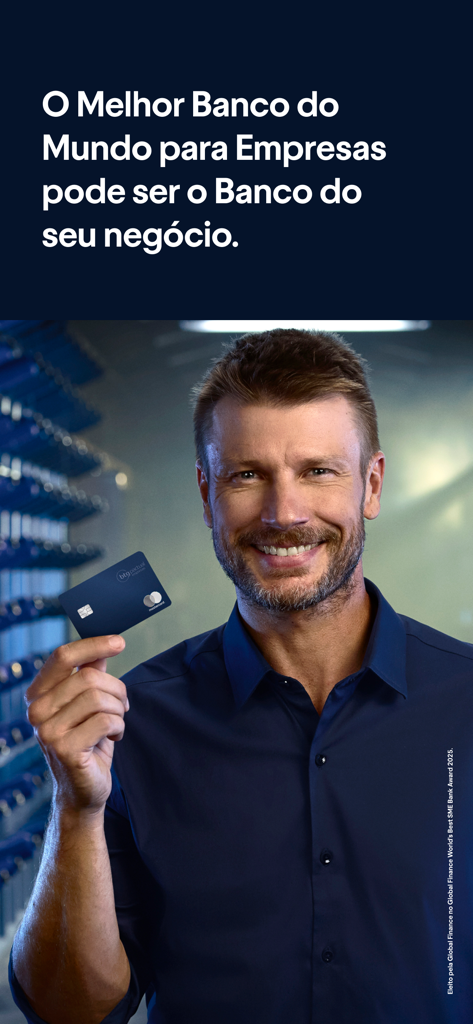 Um homem sorrindo segurando um cartão de crédito empresarial BTG Pactual Empresas