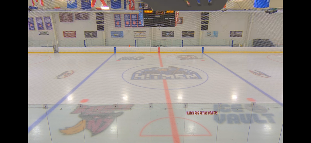 Una pista da hockey su ghiaccio vuota con i loghi delle squadre visti attraverso una telecamera di live streaming