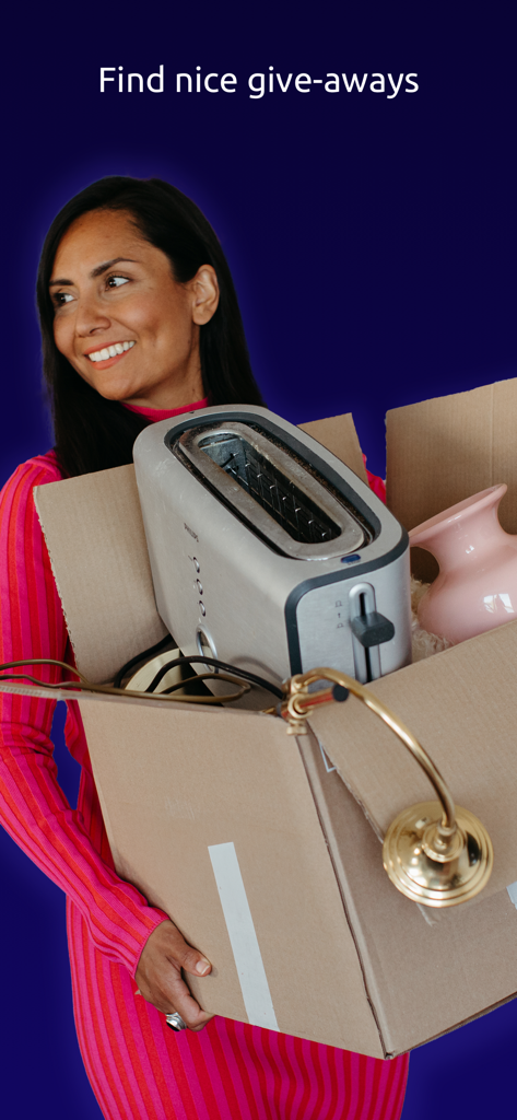 A smiling woman holding a cardboard box filled with household items for giveaway