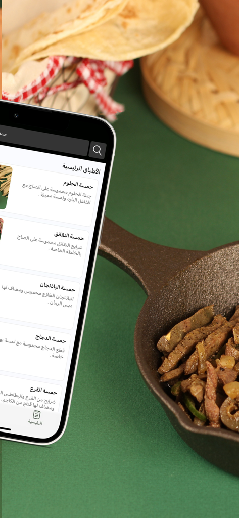 حمسات | Hamsat - Un smartphone affichant le menu de l'application Hamsat à côté d'une poêle en fonte de viande sautée et de pain plat.