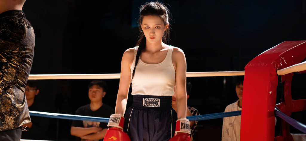 Una joven decidida con equipo de boxeo de pie en un ring de boxeo de un juego de drama interactivo.