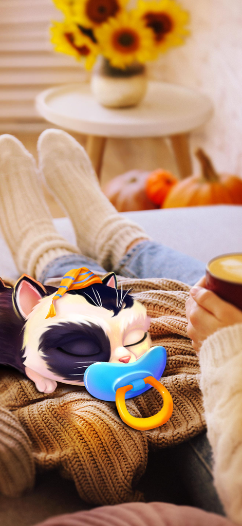 A virtual kitten with a blue pacifier sleeping on a person's lap in a cozy room with autumn decorations