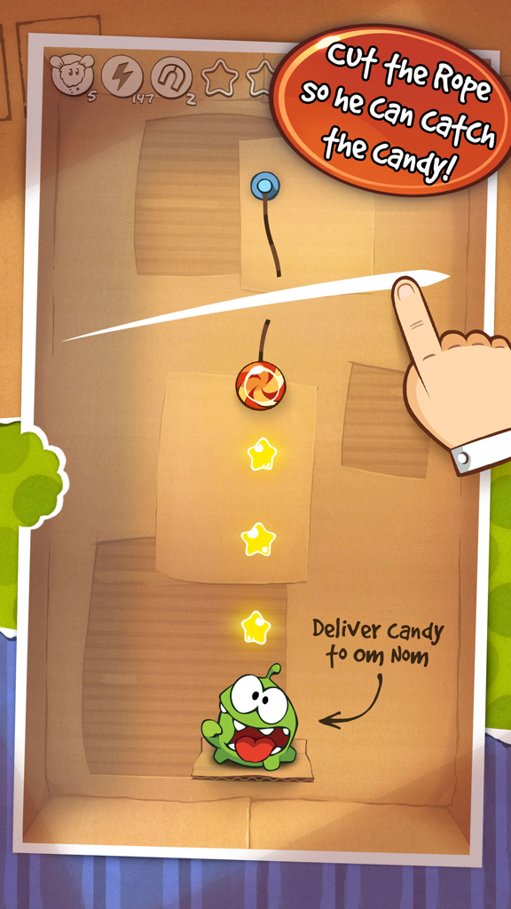 Cut the Rope GOLD - A hand swiping to cut a rope and drop candy into Om Nom's mouth in a cardboard box level