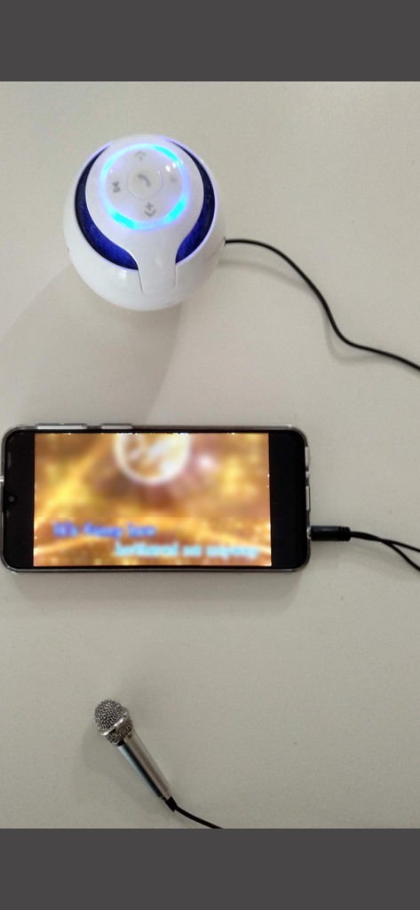 Smartphone connected to a mini microphone and a portable speaker for a mobile karaoke setup