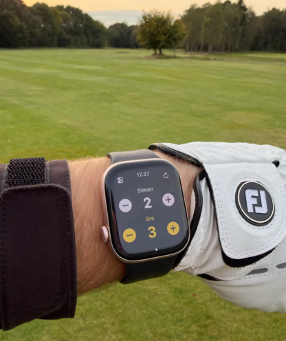 Stroke Counter for Golf - Person trägt eine Apple Watch, auf der die Schlagzähler für Golf-App angezeigt wird, während sie auf einem Golfplatz steht