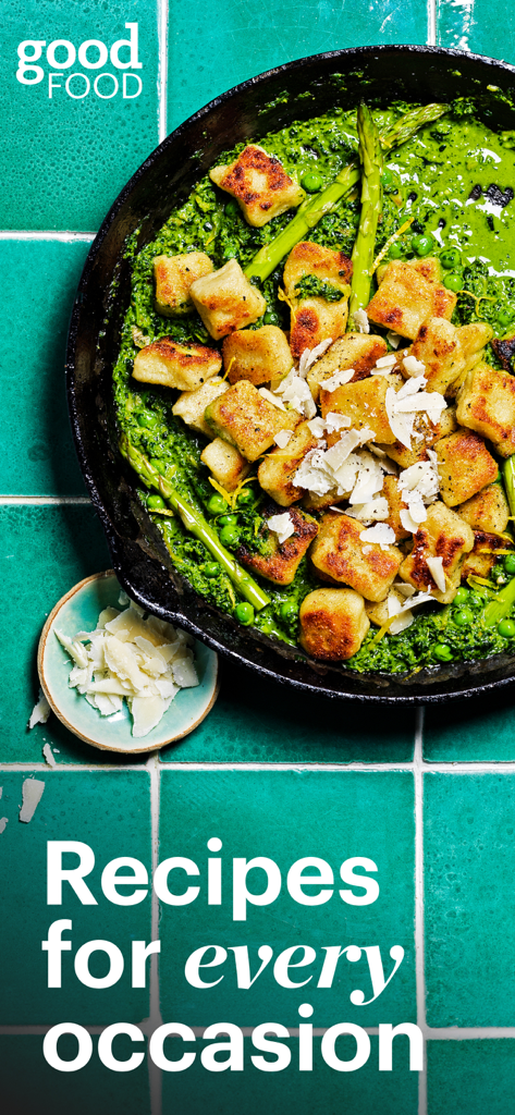 Une poêle en fonte avec des gnocchis poêlés et des asperges dans une sauce verte vibrante sur une surface carrelée bleu sarcelle.