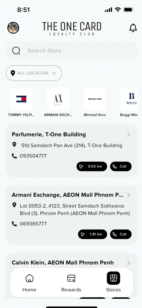 Interface do aplicativo The One Card Loyalty Club mostrando locais de lojas e logotipos de marcas premium como Michael Kors e Tommy Hilfiger.