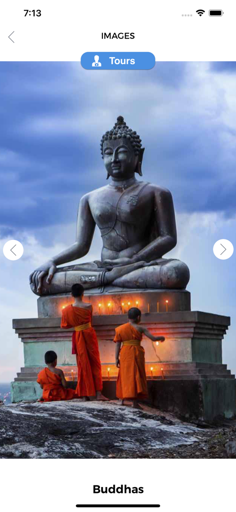 Buddhism Complete Guide - Una gran estatua de Buda de piedra con monjes con túnicas naranjas encendiendo velas en la base.