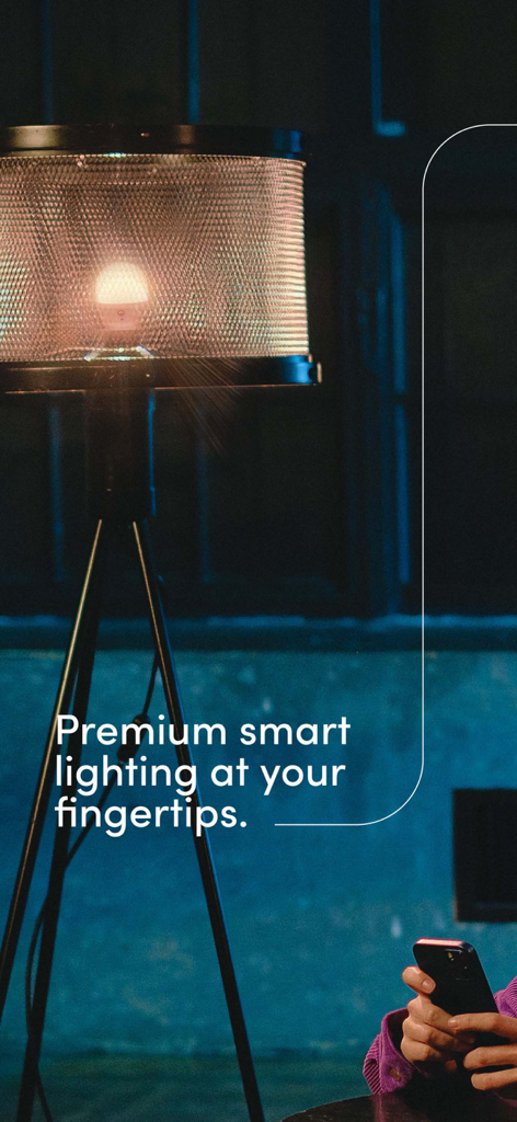 Una persona usando un smartphone para controlar una bombilla inteligente LIFX en una lámpara de trípode moderna.