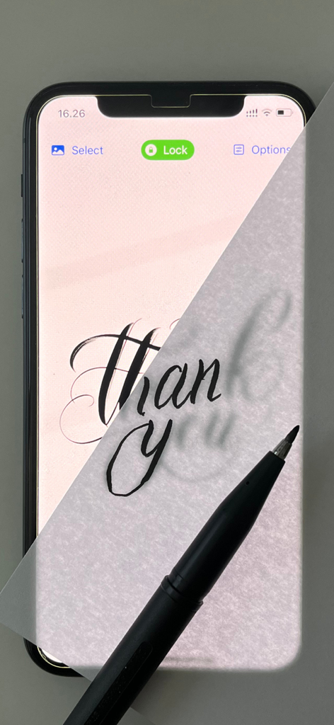 A person tracing calligraphy on a piece of paper placed over an iPhone screen using the Lightbox Tracing Pad app