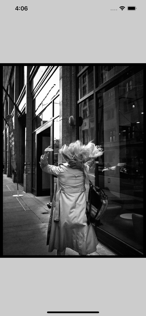 Lis-a - Black and white photo of a woman in a trench coat walking on an urban sidewalk next to a glass building