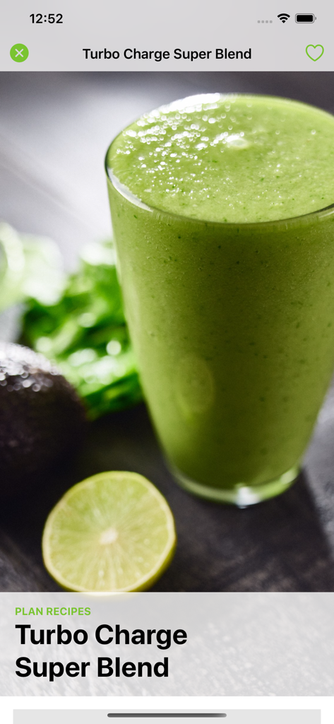 A glass of Turbo Charge Super Blend green smoothie with a lime and avocado in the background