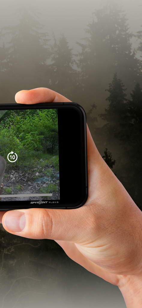 A person holding a smartphone showing a trail camera video feed with a misty forest background