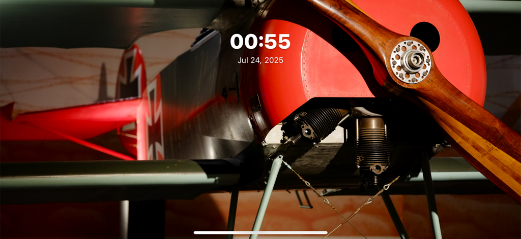 FotoSlide app displaying a vintage airplane photo with a minimalist digital clock and date overlay.
