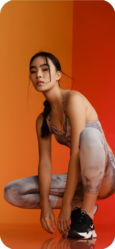 Sport Point: обувь и одежда - Mujer con leggings y sujetador deportivo de estampado de mármol agachada contra un fondo naranja