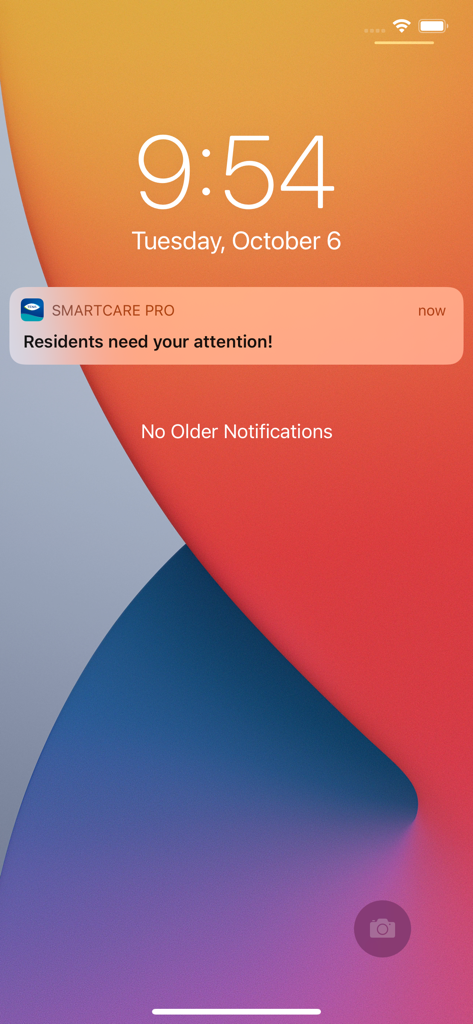 Pantalla de bloqueo del teléfono móvil que muestra una notificación de TENA Smartcare Pro indicando que los residentes necesitan atención.