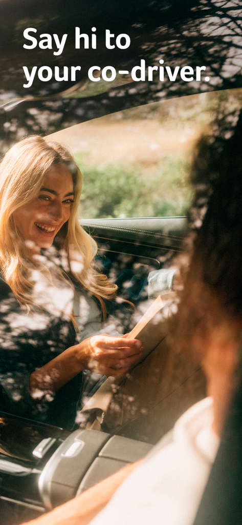 A smiling woman in the passenger seat of a vehicle with the text Say hi to your co-driver.
