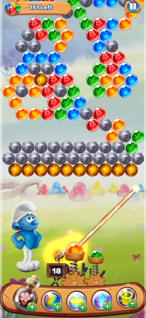 A Smurf character aiming a bubble launcher in a colorful puzzle level with mushroom houses in the background.