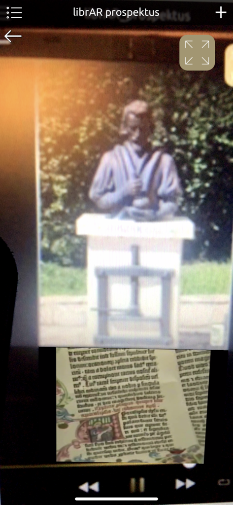 Augmented reality view of a Johannes Gutenberg statue appearing above a printed book page in the librAR app