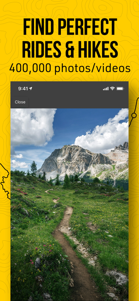 Un sendero sinuoso para ciclismo de montaña y senderismo a través de un prado verde con picos rocosos al fondo.