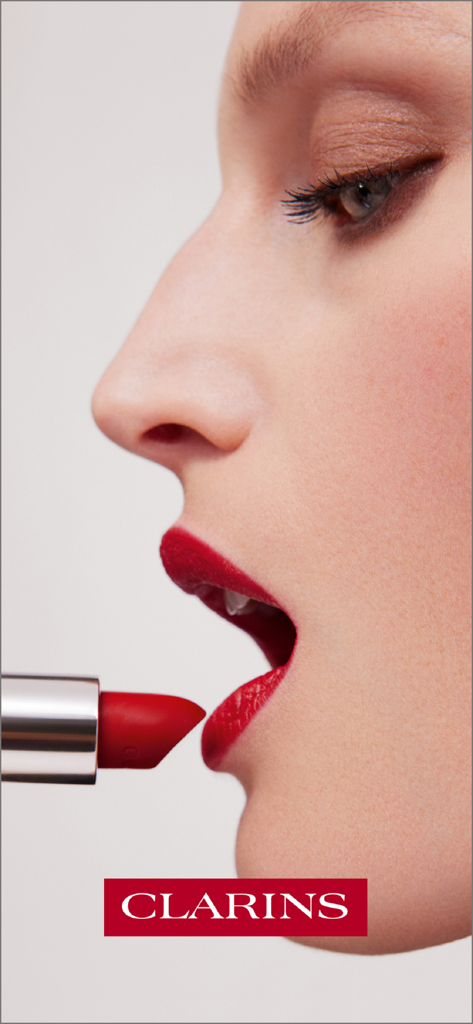 Clarins - Skincare and Makeup - Gros plan du profil d'une femme appliquant du rouge à lèvres rouge Clarins
