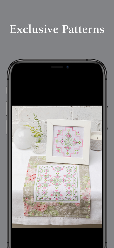 Mobile screen showing exclusive cross-stitch patterns with a framed floral design and matching table runner