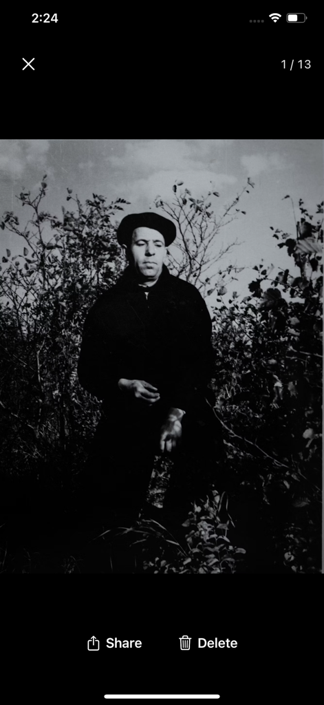 A black and white vintage photo filter applied to a man wearing a beret sitting in nature.