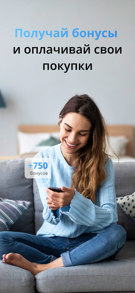 СТОЛПЛИТ – гипермаркет мебели - A woman using the Stolplit app on her phone to earn and spend shopping bonuses while sitting on a sofa