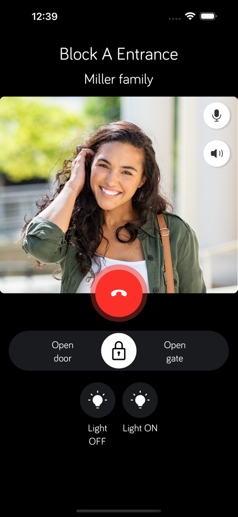 Urmet CallMe Uin - Interface do aplicativo Urmet CallMe Uin mostrando uma chamada de vídeo de uma entrada de prédio com botões remotos de destravamento de porta e portão