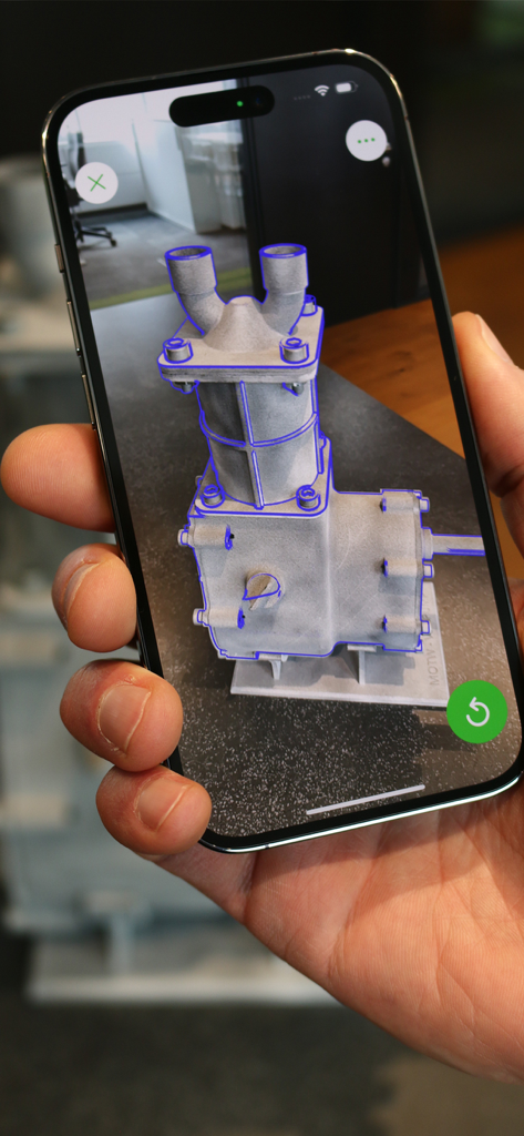 Una persona sostiene un teléfono inteligente con Vuforia Creator para probar una superposición de objetivo de modelo de realidad aumentada en una pieza industrial física