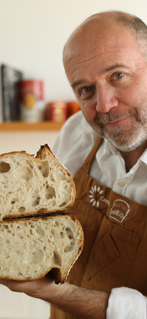 Un homme tenant une miche de pain au levain artisanal tranchée avec une mie aérée.