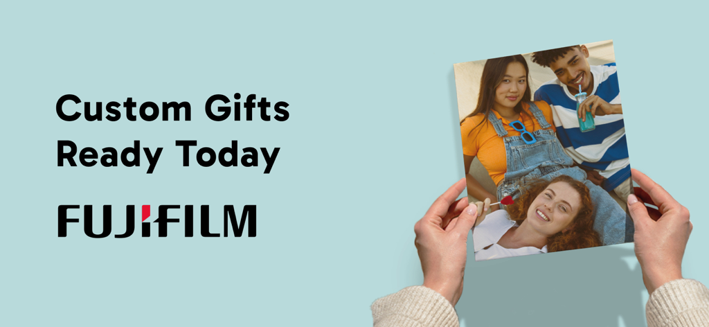 Des mains tenant un grand tirage photo personnalisé de trois amis à côté du logo Fujifilm.