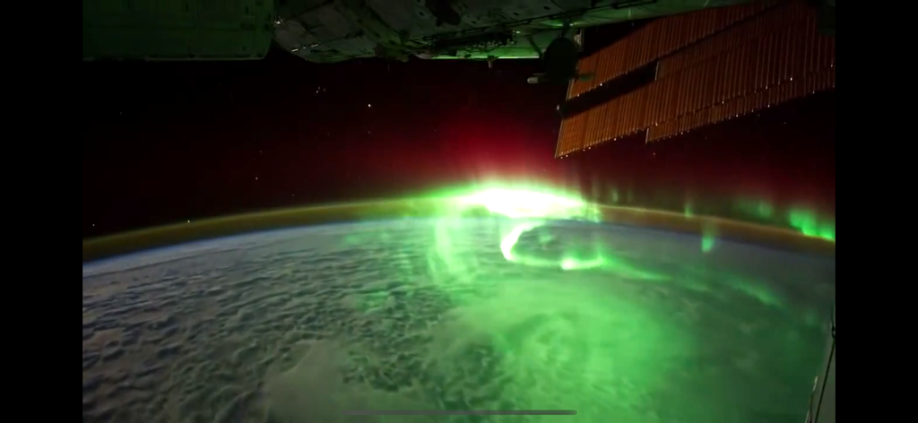Solar Alert: Protect your Life - Satellite view of a green aurora borealis glowing over Earth from space