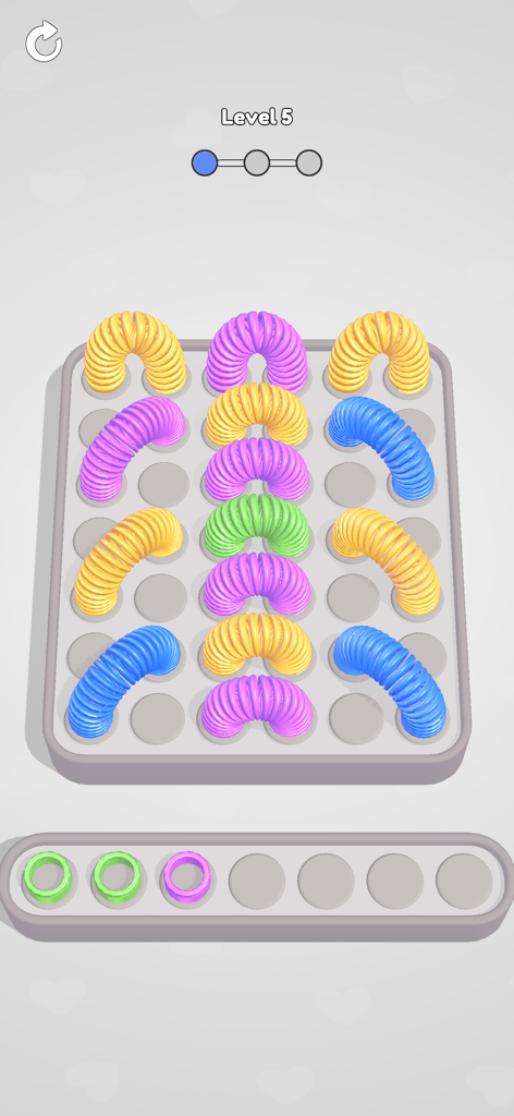 Gameplay screenshot of Slinky Jam showing colorful slinky toys on a sorting grid for level five.