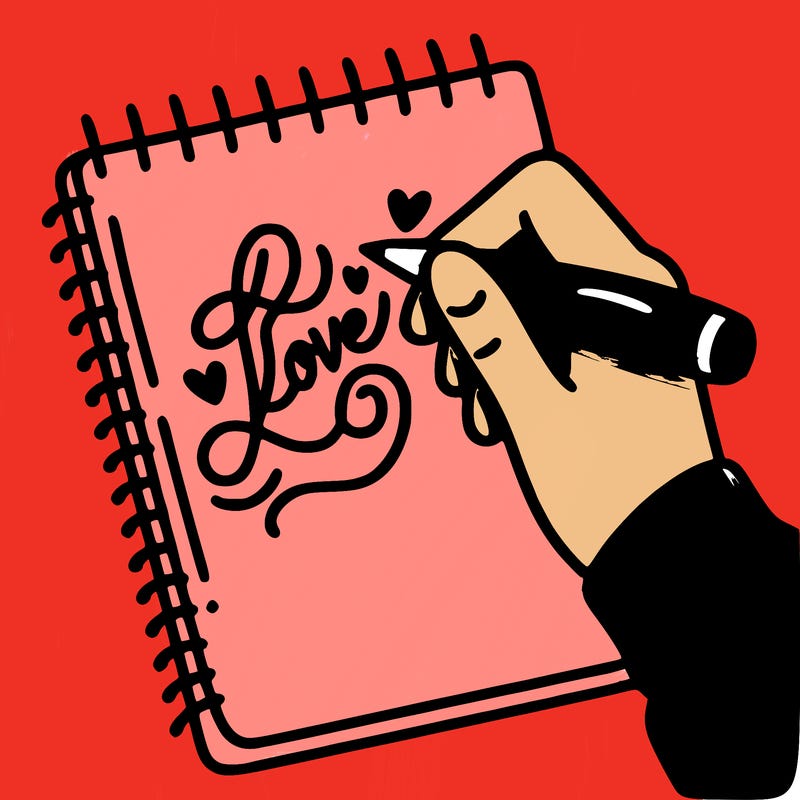 a hand writing “love” in calligraphy on a notebook