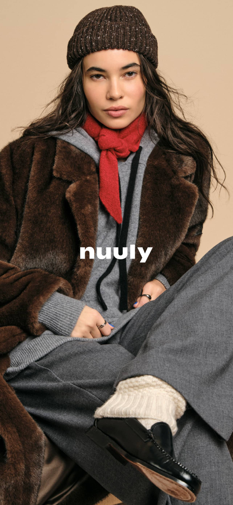 A woman modeling a layered winter outfit with the Nuuly logo