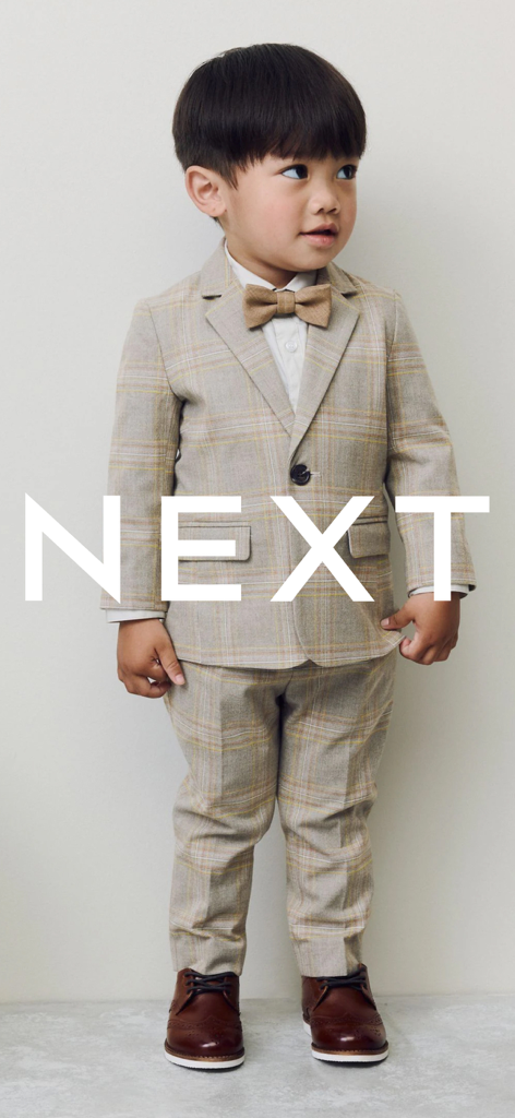 Next: Shop Fashion & Homeware - A young boy wearing a beige plaid suit and brown bowtie from the Next fashion app