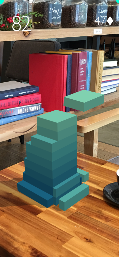 Stack AR - Stack AR mobile game showing a tower of blocks stacked on a wooden table in a cafe using augmented reality