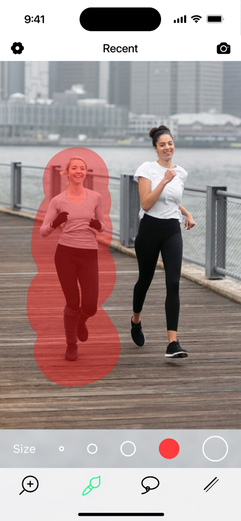 Una foto de dos mujeres corriendo donde una está resaltada en rojo para ser eliminada con la herramienta de borrador de objetos IA.