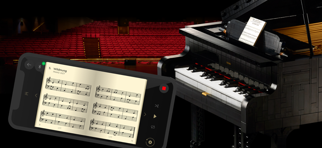 A smartphone displaying sheet music via the LEGO Powered Up app next to a LEGO Grand Piano in a concert hall