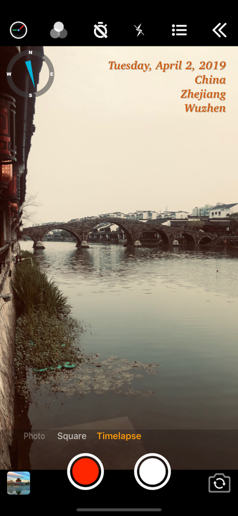 Screenshot der Benutzeroberfläche der Timestamp Camera Basic App mit einem Echtzeit-Datums- und Standort-Wasserzeichen auf einem Foto einer Steinbrücke.