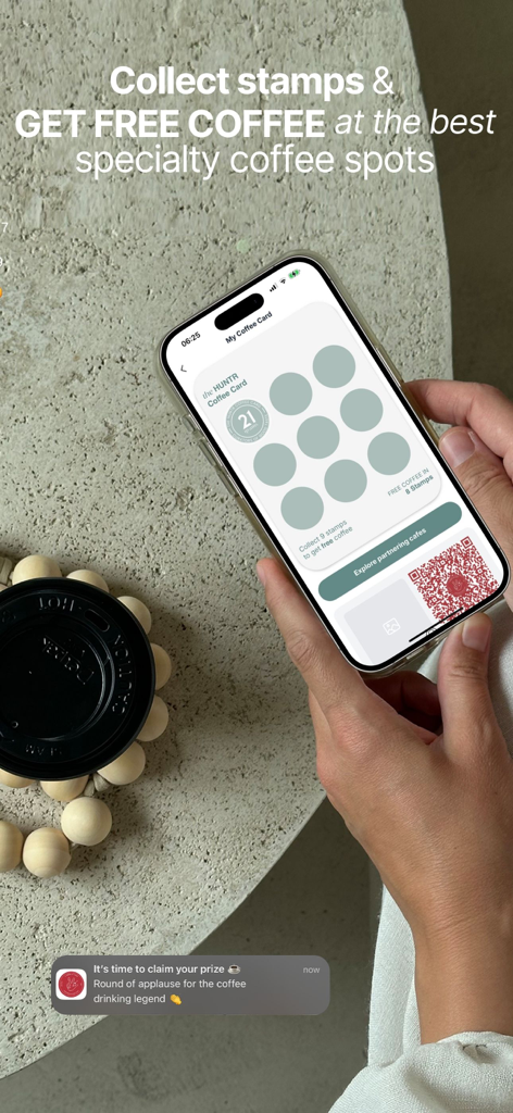The HUNTR: City Guide - A person holding a smartphone displaying the digital coffee loyalty card feature in The HUNTR app