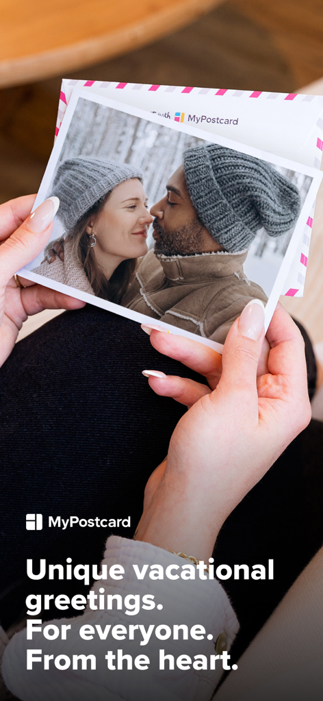 Une main tenant une carte postale photo personnalisée représentant un couple dans une forêt enneigée, avec le texte « Vœux de vacances uniques ».